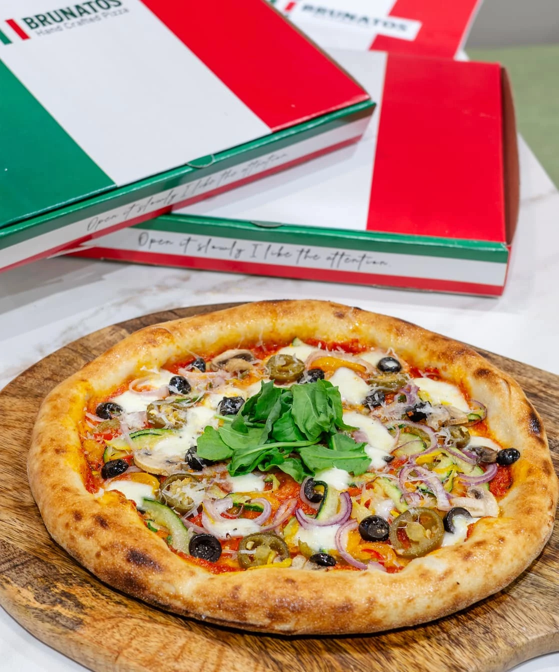Handcrafted Brunatos pizza topped with vegetables and fresh basil